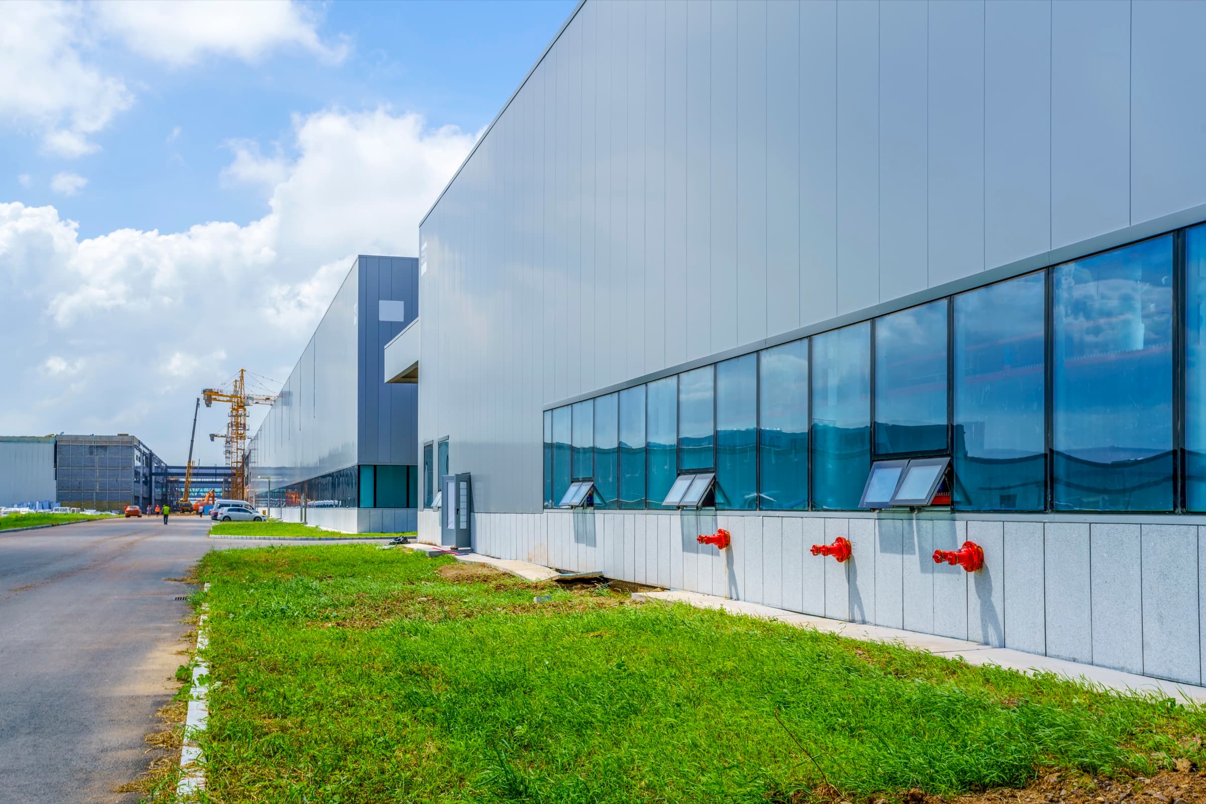 Large industrial unit with grey metal cladding and a long run of glazing, on a landscaped industrial estate